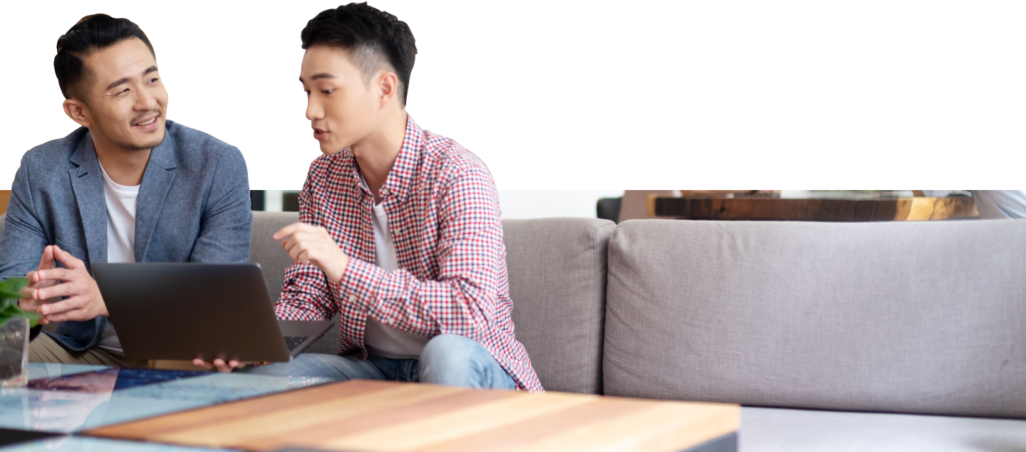 Two coworkers sitting on a couch reviewing something on a laptop. 