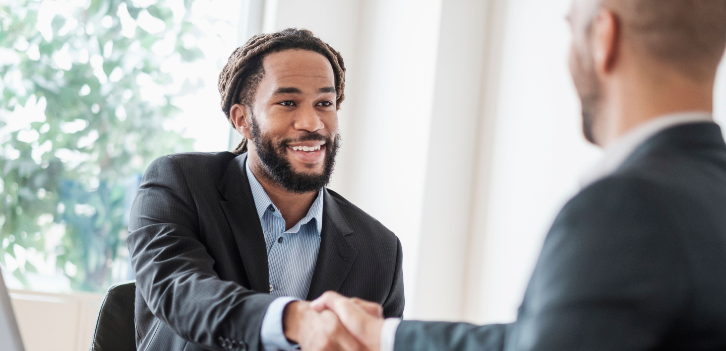 Two men wearing business suits shaking hands. 