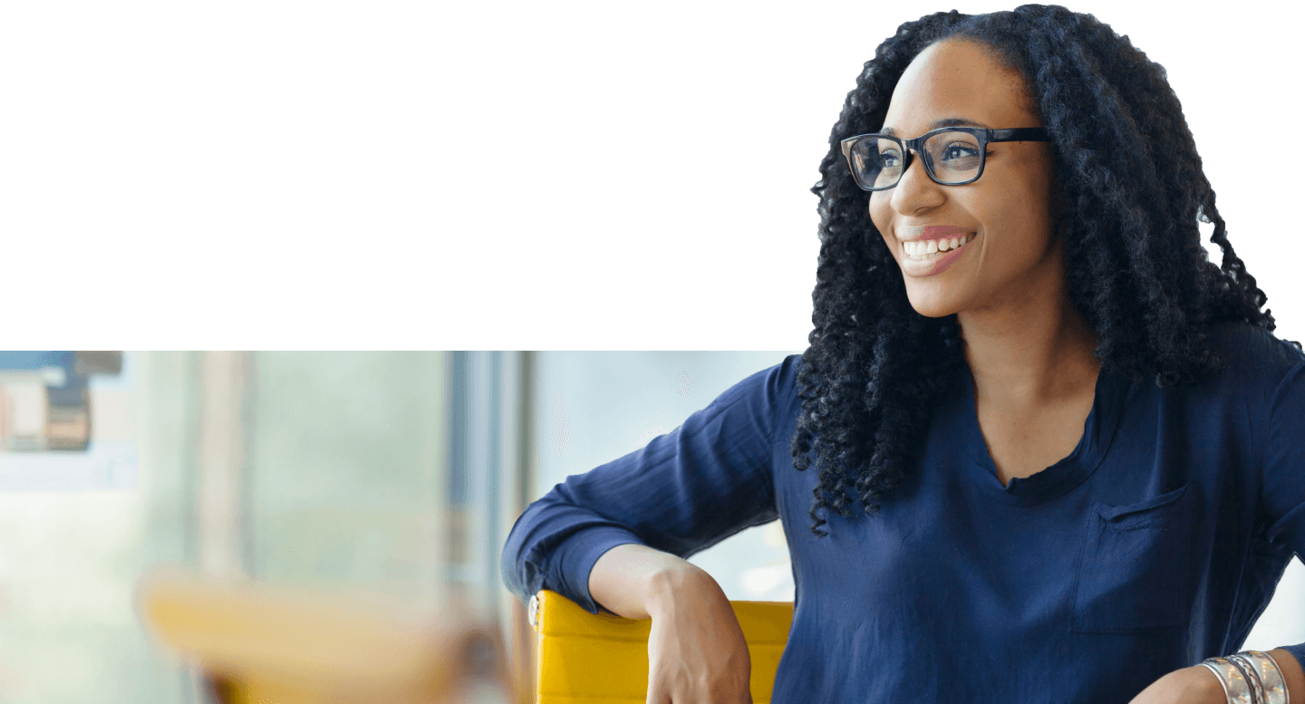 Close-up of a women wearing glasses and smiling while sitting in a yellow office chair.