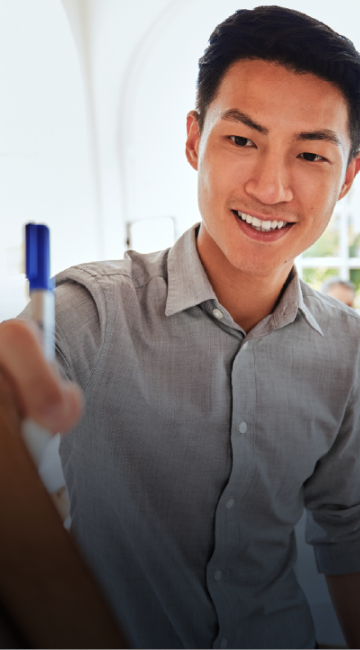 Close-up of a smiling man writing something on a whiteboard. 